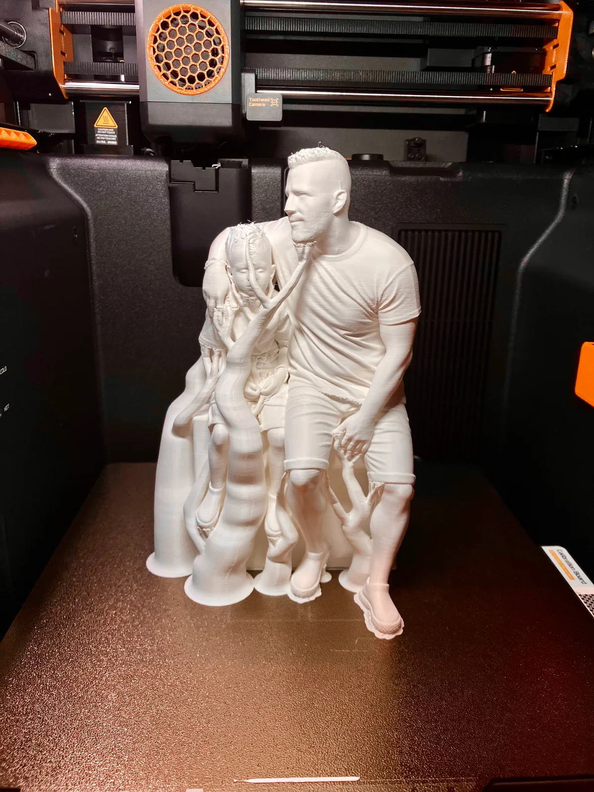 White family figurine on the print bed with supports still attached
