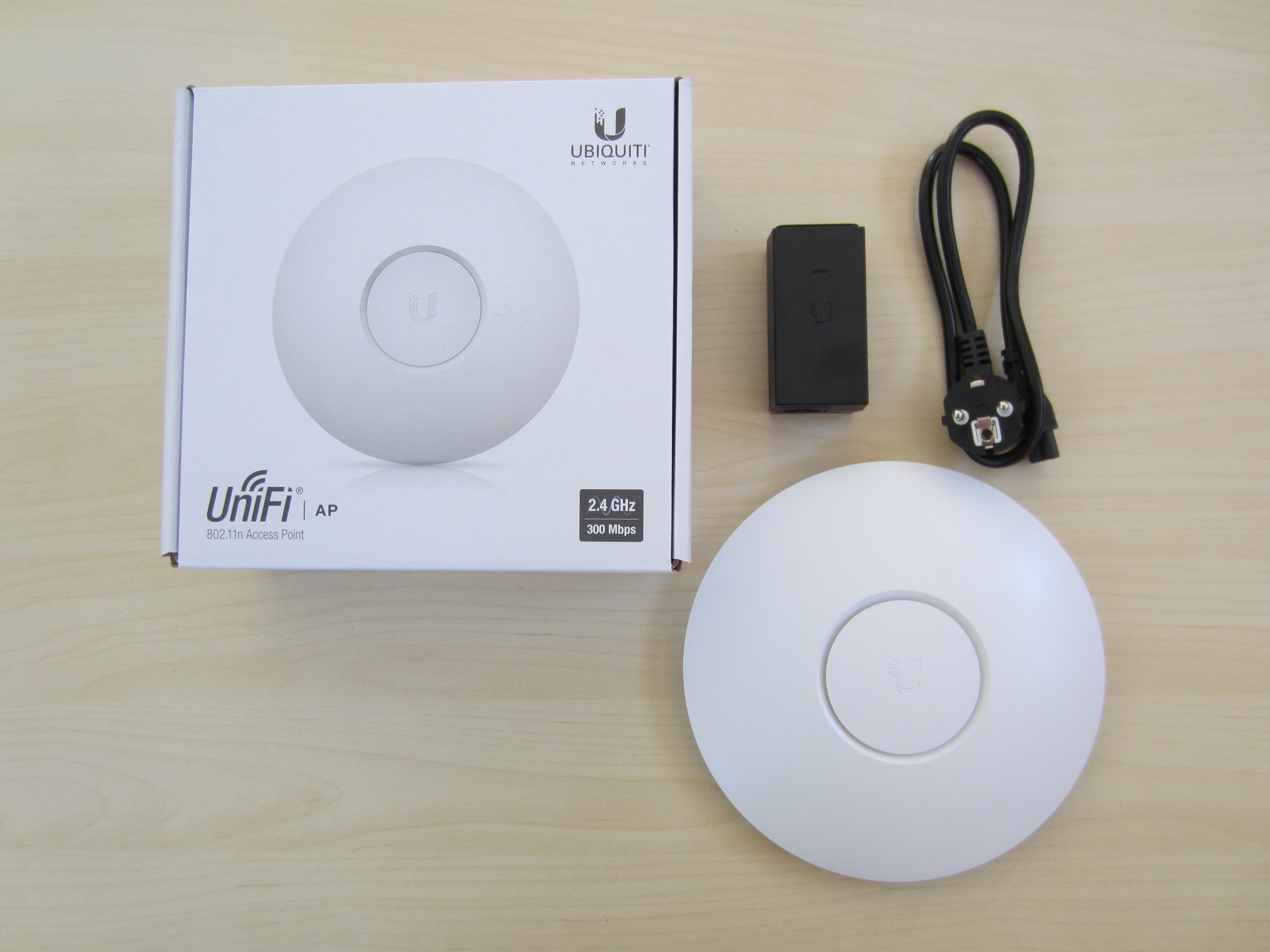 A white UniFi wireless access point and its packaging